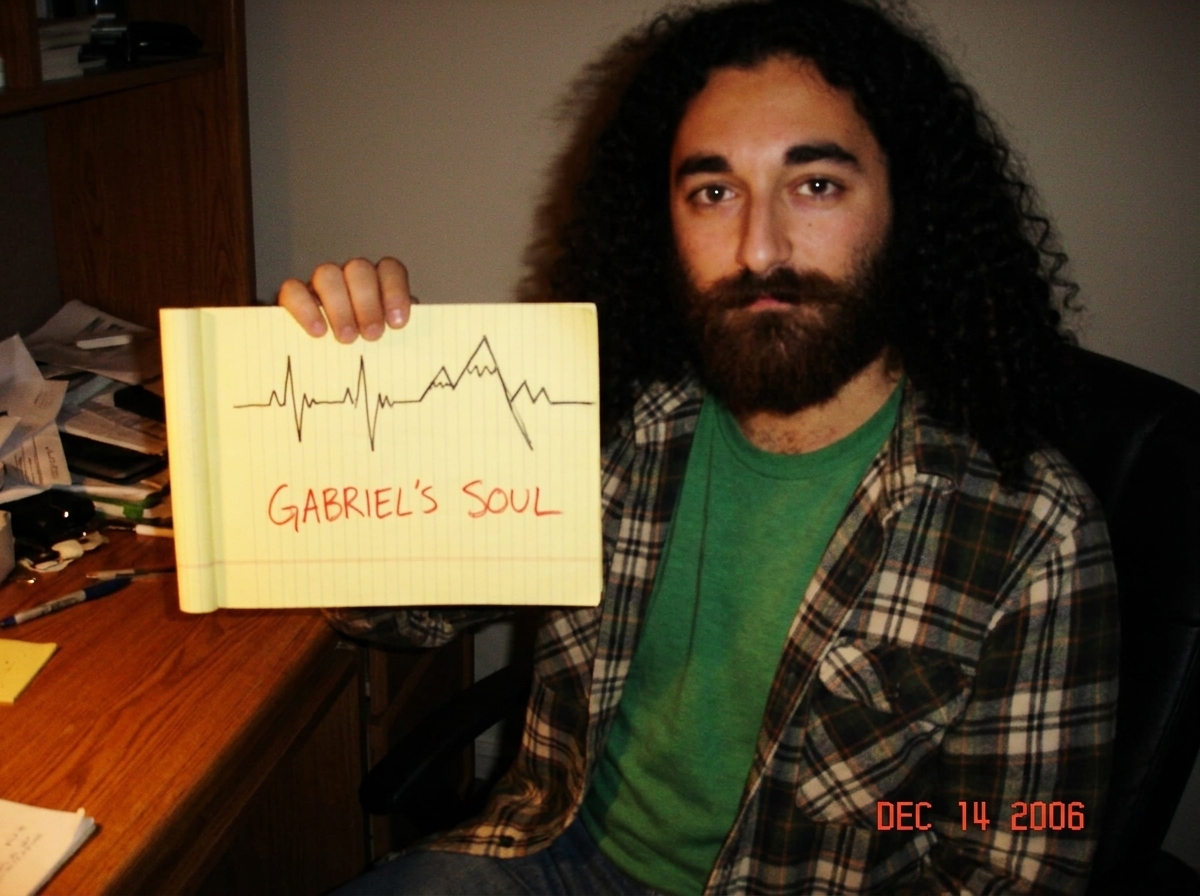 A hand-drawn sketch on yellow legal pad paper showing three squiggly lines that vaguely resemble a heartbeat monitor and a mountain range, with the label 'GABRIEL'S SOUL' written in shaky red marker at the bottom