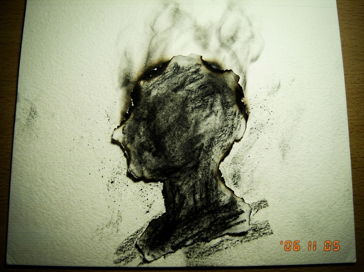A close-up, gritty charcoal drawing of a blackened scrap of paper in the shape of a vague profile, smoke rising from the edges.