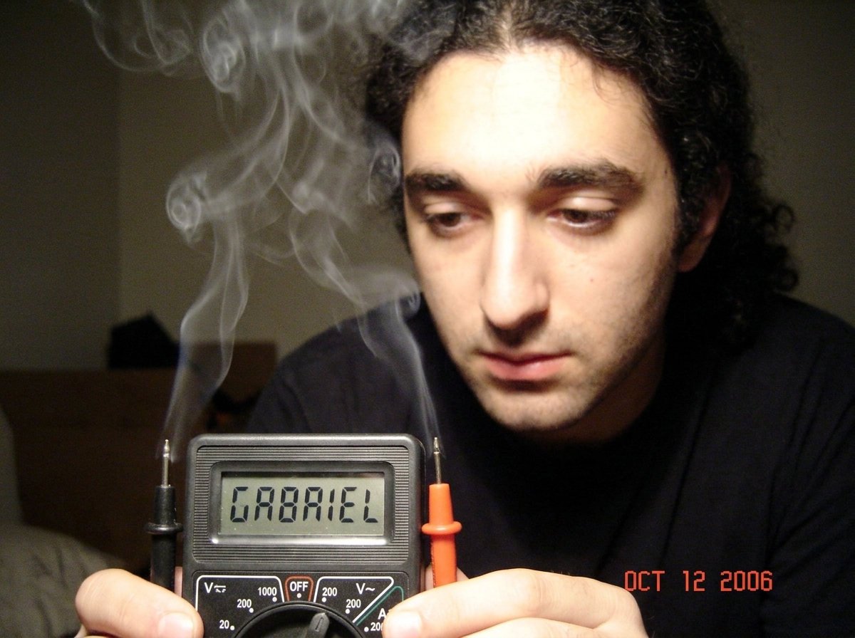 a close up of a multimeter display reading 'GABRIEL' with smoke rising from the probes