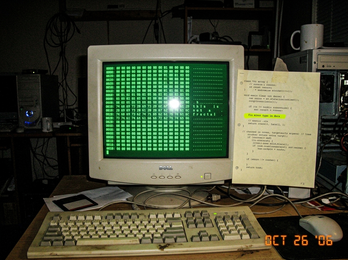 A screenshot of a hex dump reading 'this is not a fractal' in ASCII, with the line 'fix minor typo in docs' highlighted in yellow, next to a crt monitor glowing green