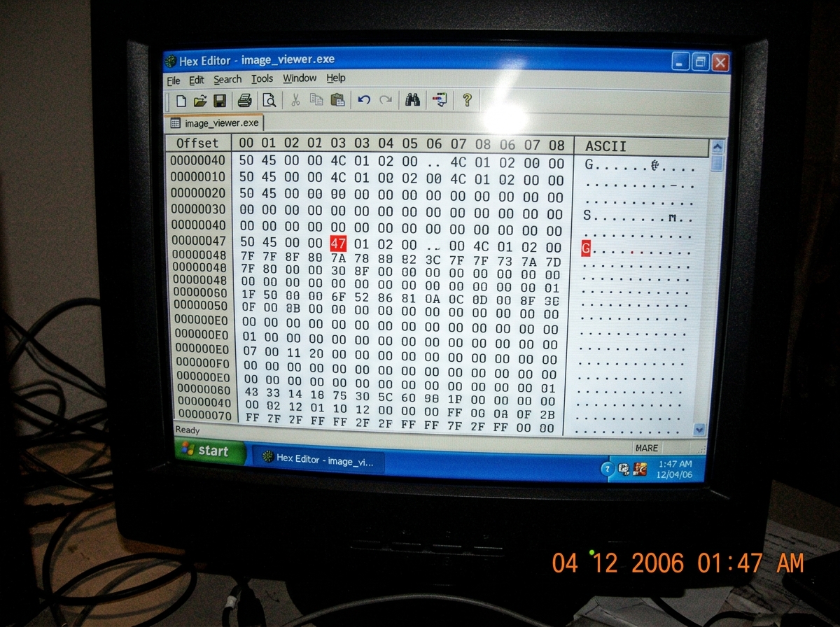 Grainy photo of a computer screen showing a hex editor with 0x47 highlighted at offset 0x47 in red, timestamp 1:47 AM visible in the corner, slightly blurry and overexposed as if taken with a cheap phone camera
