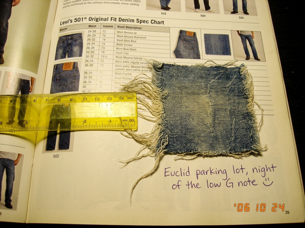 A small faded denim patch with frayed threads, laid on a yellowed 2003 fashion catalog page open to the Levi's denim spec chart. A yellow plastic ruler measures the threads. A handwritten note in purple ink reads 'Euclid parking lot, night of the low G note' and a smiley face.