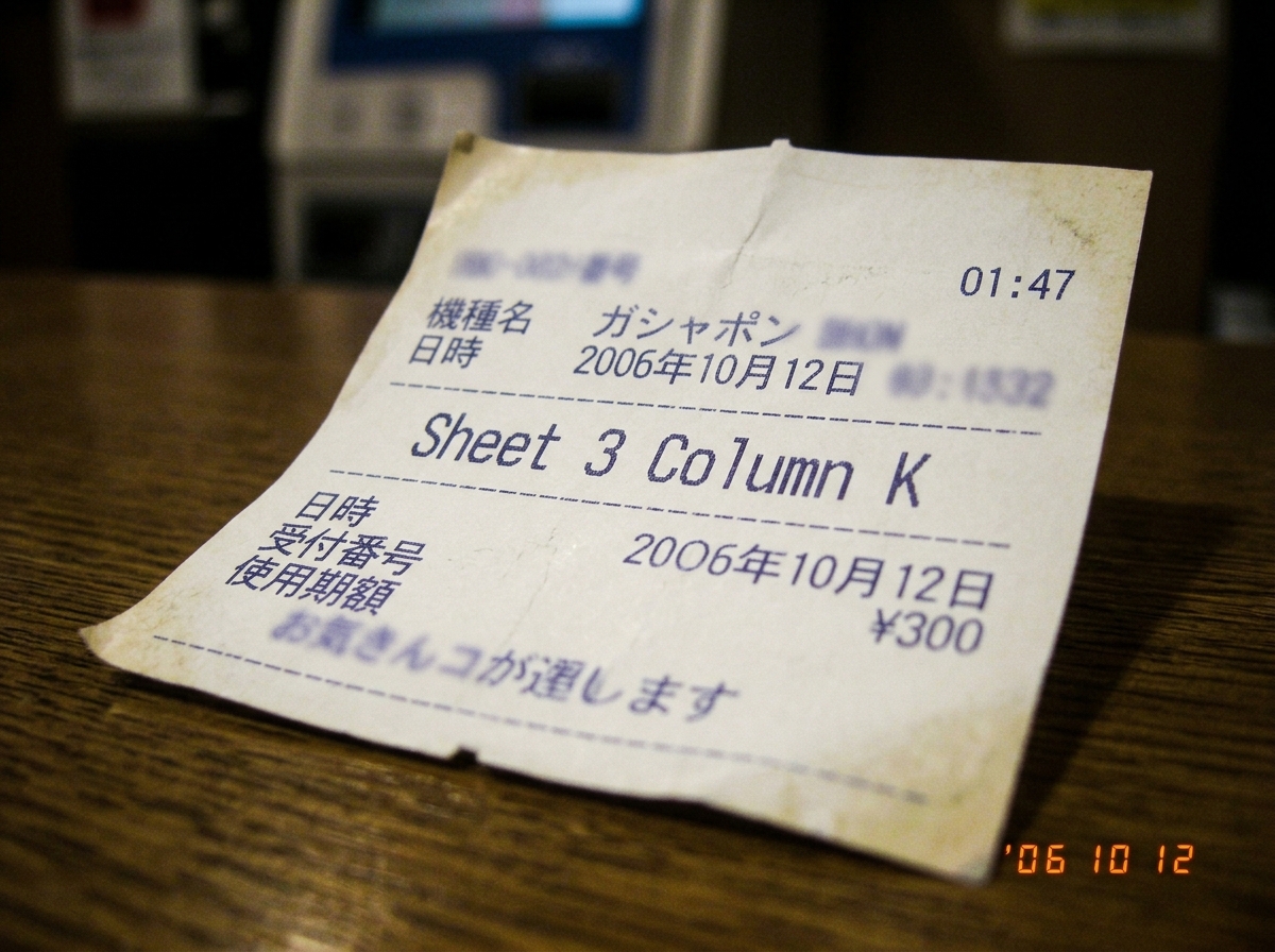 A close-up of a thermal printer paper receipt from a Japanese kiosk, showing faded blue printing with 'Sheet 3 Column K' clearly visible and a timestamp '01:47' in the corner. The paper has slight curl and thermal fading at the edges, with faint grid lines visible. The background is softly blurred t
