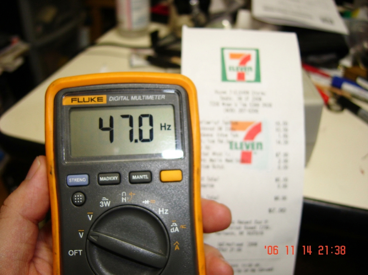 Close-up photo of a Fluke multimeter display showing '47.0 Hz' with a blurry background of a 7-Eleven receipt