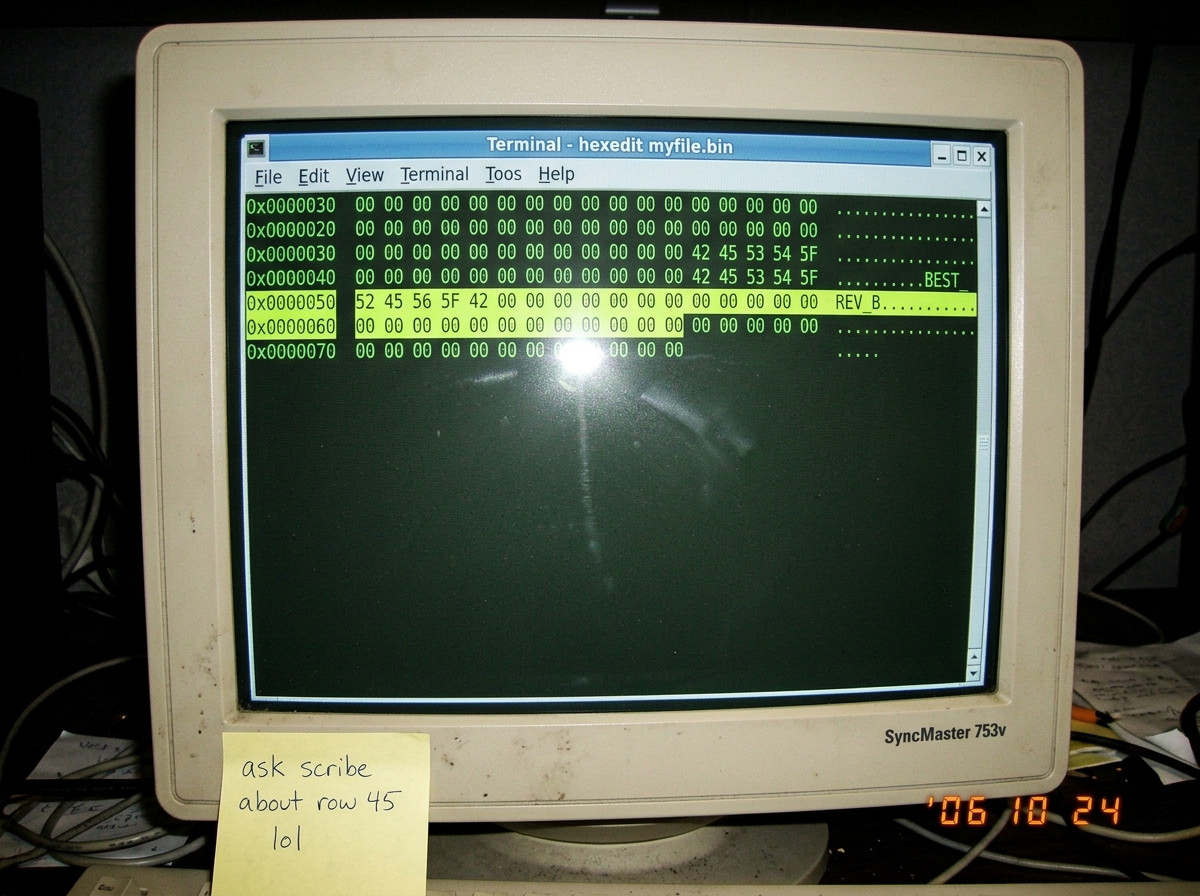 A screenshot of a hex dump in a terminal window, with three lines highlighted - at offset 0x4B the ASCII column shows 'REV_B' surrounded by padding zeros. The terminal background is dark green on black. A sticky note on the monitor bezel reads 'ask scribe about row 45 lol'.