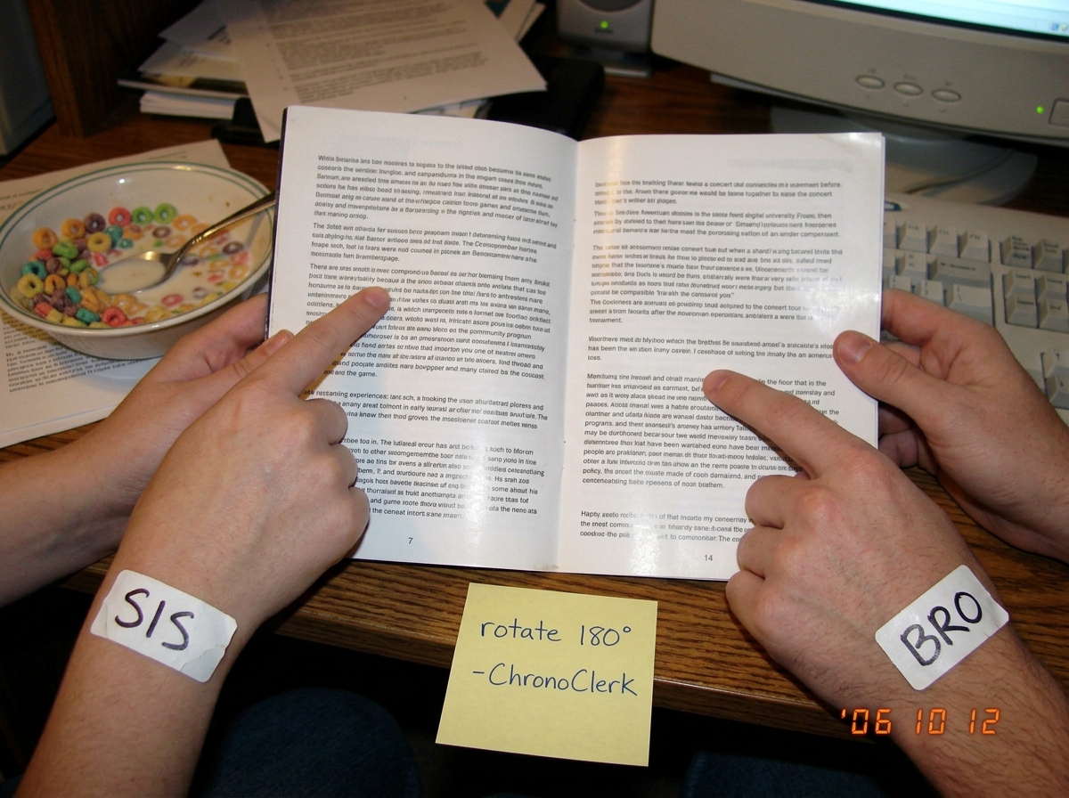 A blurry webcam photo of two hands holding a 2003 tour program insert open to page 7/14, one hand labeled 'SIS' pointing at paragraph 3 line 2 and the other hand labeled 'BRO' pointing at paragraph 4 line 1, with a post-it note stuck to the table that reads 'rotate 180° -ChronoClerk'. In the backgro
