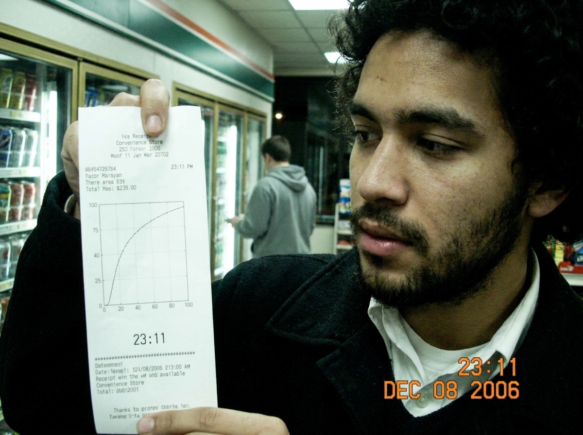 A printed receipt on a convenience store counter showing a gamma curve graph. In the background, a shadowy figure in a gray hoodie stands near the refrigerated section, slightly out of focus. The timestamp on the receipt reads 23:11.