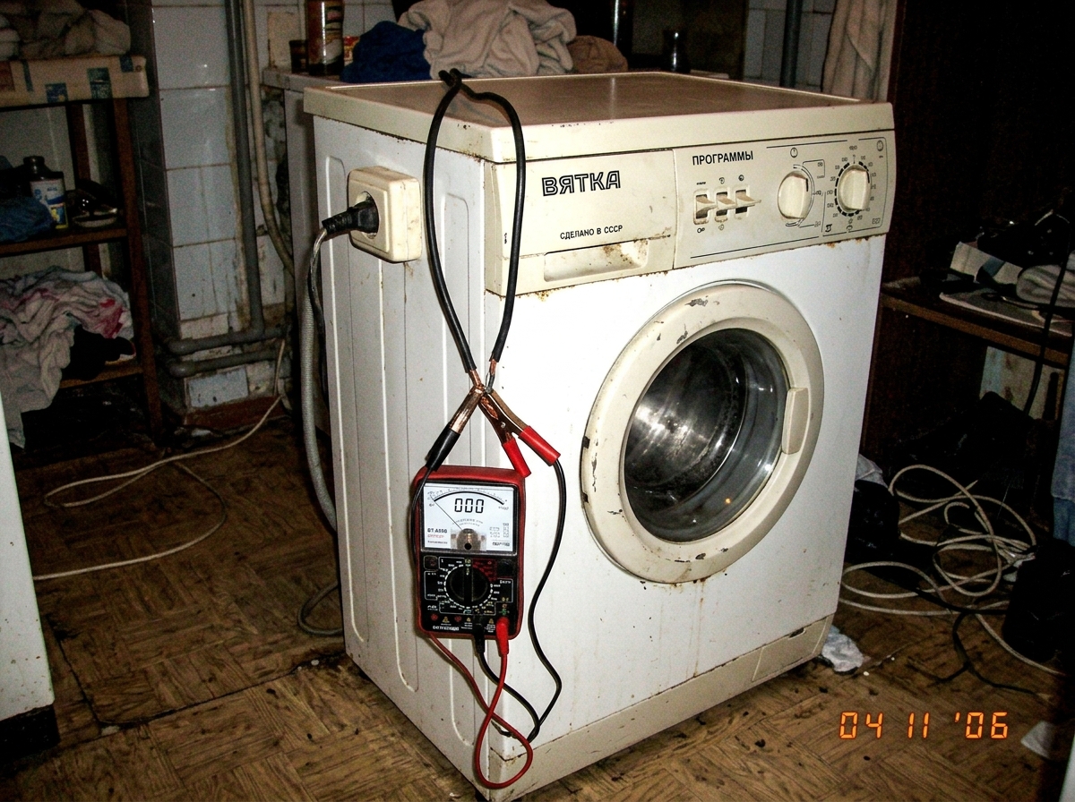 A low-res photo of a Soviet-era washing machine with a multimeter clipped to its power cord