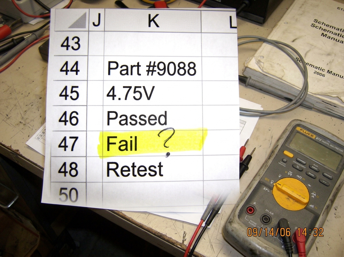 Cell phone photo of a printed spreadsheet showing column K, rows 44-48. Row 47 cell is highlighted in yellow with a question mark written in pen. My Fluke 87V is visible in the corner of the frame.