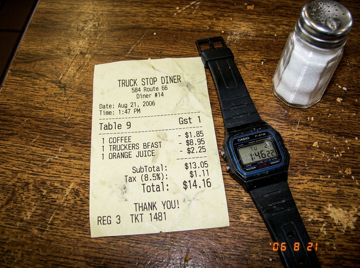 A crumpled receipt from a truckstop diner dated Aug 21, 2006, with the timecode 1:47 PM, printed on thermal paper that's partially faded. Next to it is a scratched-up Casio wristwatch reading 1:46. The photo is taken on a worn wooden diner tabletop next to a salt shaker.