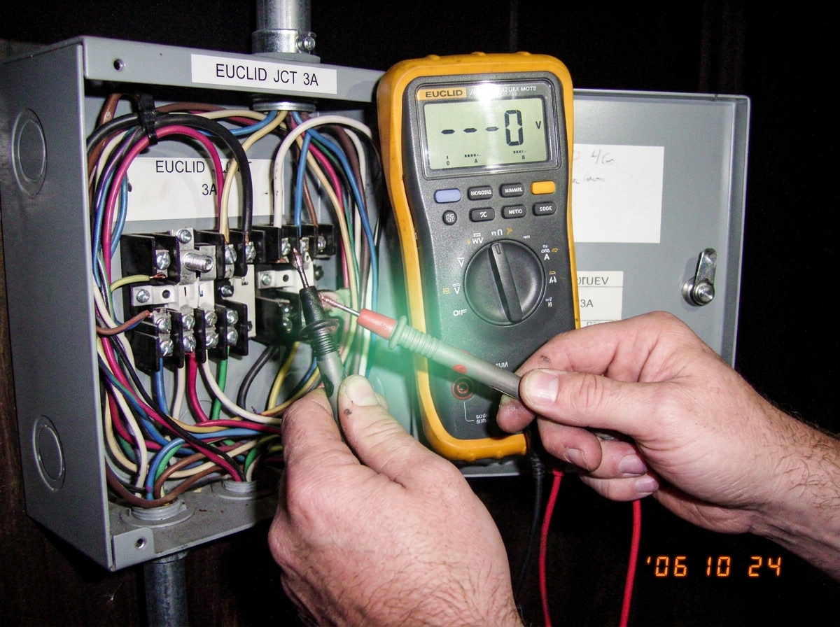 close-up of hands fused to multimeter probes at Euclid junction box, glowing faintly green