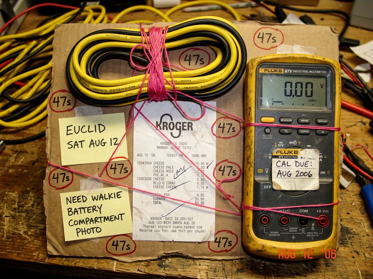 A fan shrine collage: crumpled Kroger cheese receipt, 16AWG extension cord coiled and ready, Fluke 87V multimeter with 'CAL DUE: AUG 2006' sticker, pink embroidery thread holding it all together with notes reading 'EUCLID SAT AUG 12' and 'NEED WALKIE BATTERY COMPARTMENT PHOTO' scattered with 47s cir