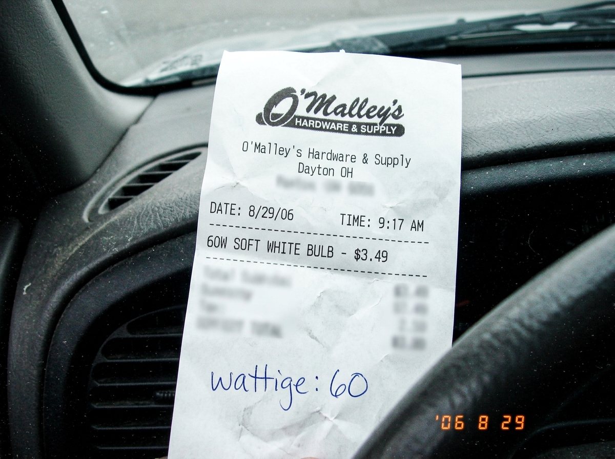 A crumpled white receipt from 'O'Malley's Hardware & Supply, Dayton OH' showing item: '60W SOFT WHITE BULB - $3.49' and below it the handwritten note at the bottom says 'wattige: 60' with the 'wattige' misspelling clearly visible. The receipt is dated 8/29/06 and the time stamp shows 9:17 AM. The re