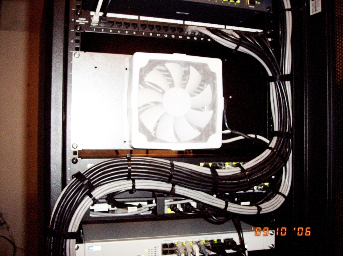A close up of a server rack with a new white fan filter installed and neatly bundled cables held together by black zip ties