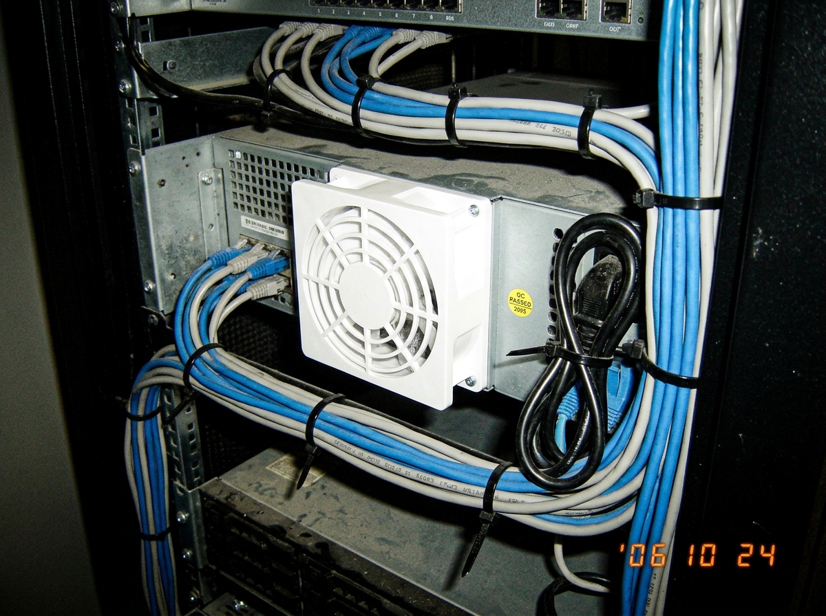 A close up of a server rack with a new white fan filter installed and neatly bundled cables held together by black zip ties