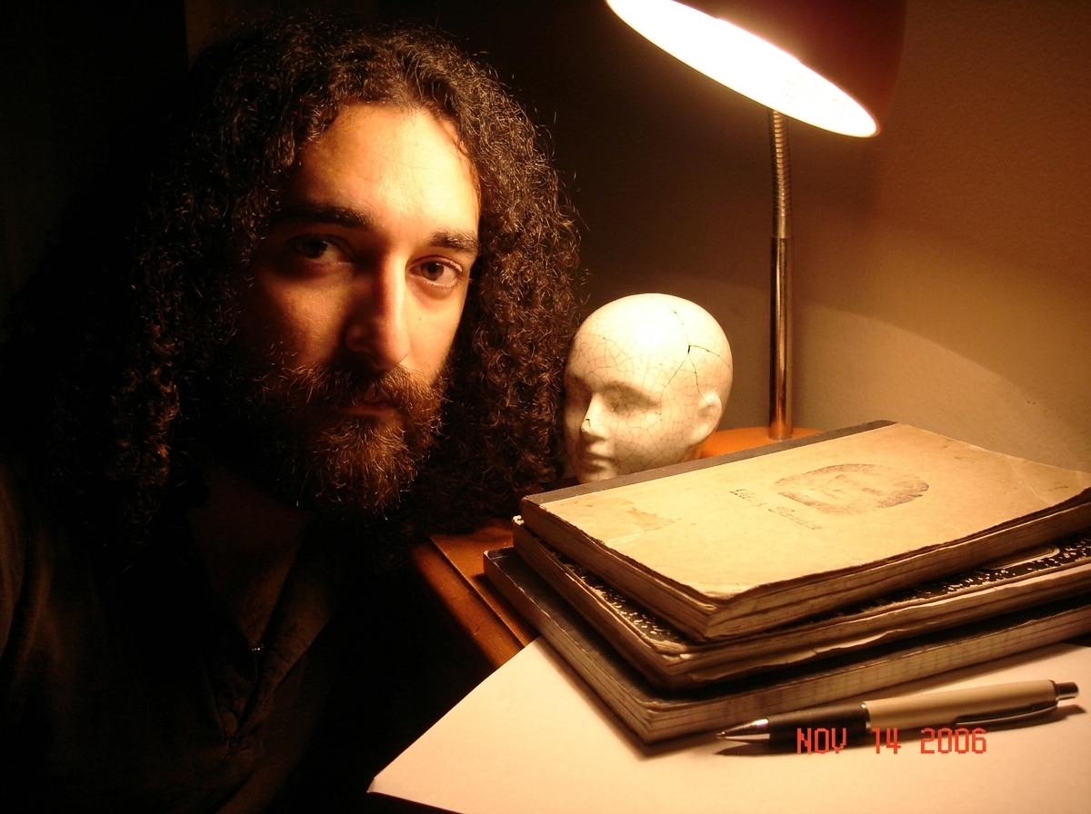 A cluttered writer's desk corner at night. A small cracked white ceramic head sits next to a stack of notebooks, catching warm lamplight. A pen lies uncapped nearby. A faint imprint is visible on a notebook cover. The scene feels intimate and slightly melancholic.