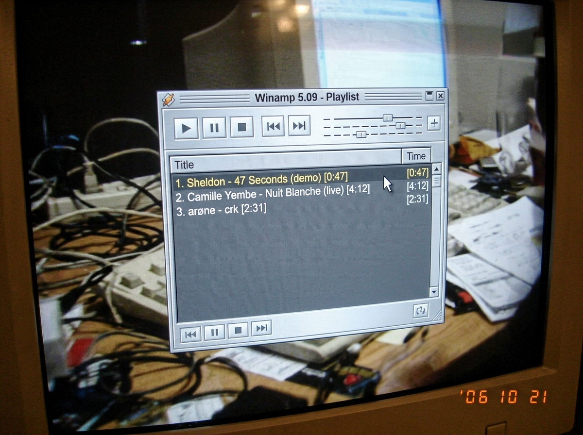 A blurry screenshot of a Winamp playlist window from 2006, showing three songs: 'Sheldon - 47 Seconds (demo)', 'Camille Yembe - Nuit Blanche (live)', 'arøne - crk'. The cursor is hovering over the track length column. The window has that classic Winamp silver skin and is slightly overexposed.