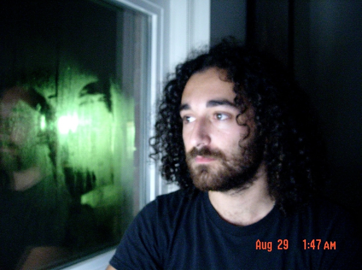 Blurry cell phone photo of a window with bright green reflection in it, dark room, timestamp Aug 29 1:47 AM visible in corner