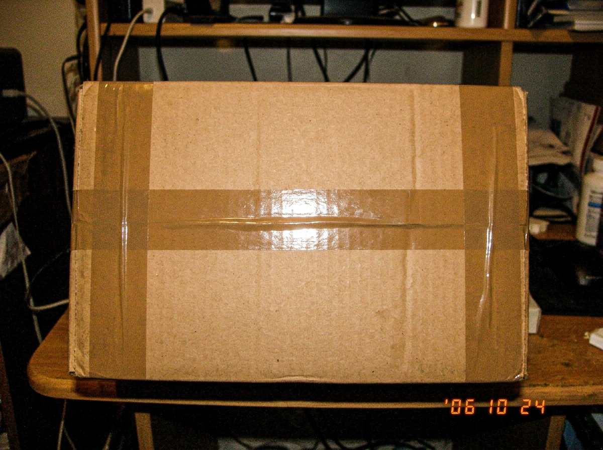 A close-up of a perfectly taped box with symmetrical tape lines, taken with a cheap digital camera flash