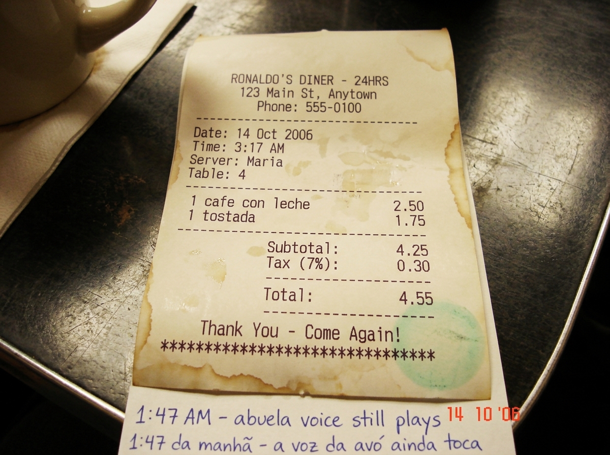 A thermal paper receipt from Ronaldo's Diner showing 'cafe con leche' purchased at 3:17 AM, faint green smudge in corner where walkie talkie glow pressed against counter, coffee-stained edges curled, handwritten '1:47 AM - abuela voice still plays' in Portuguese at bottom