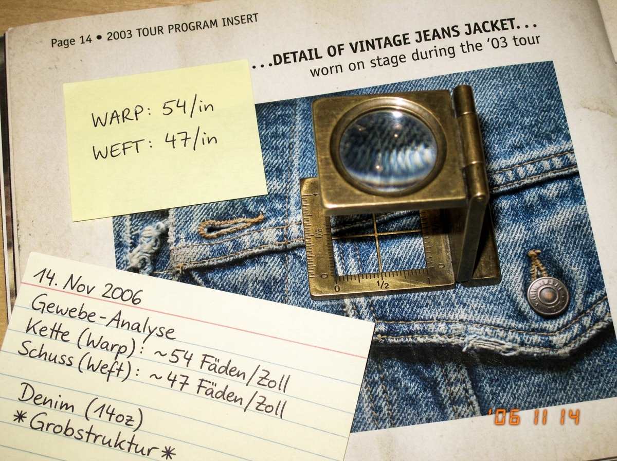 A close-up photo of a linen tester (fabric counting magnifier) resting on a printed page - the 2003 tour program insert page 14, showing a denim jacket detail. A sticky note on the page reads 'WARP: 54/in, WEFT: 47/in' in neat handwriting. The linen tester has a small ruler scale visible. An index c