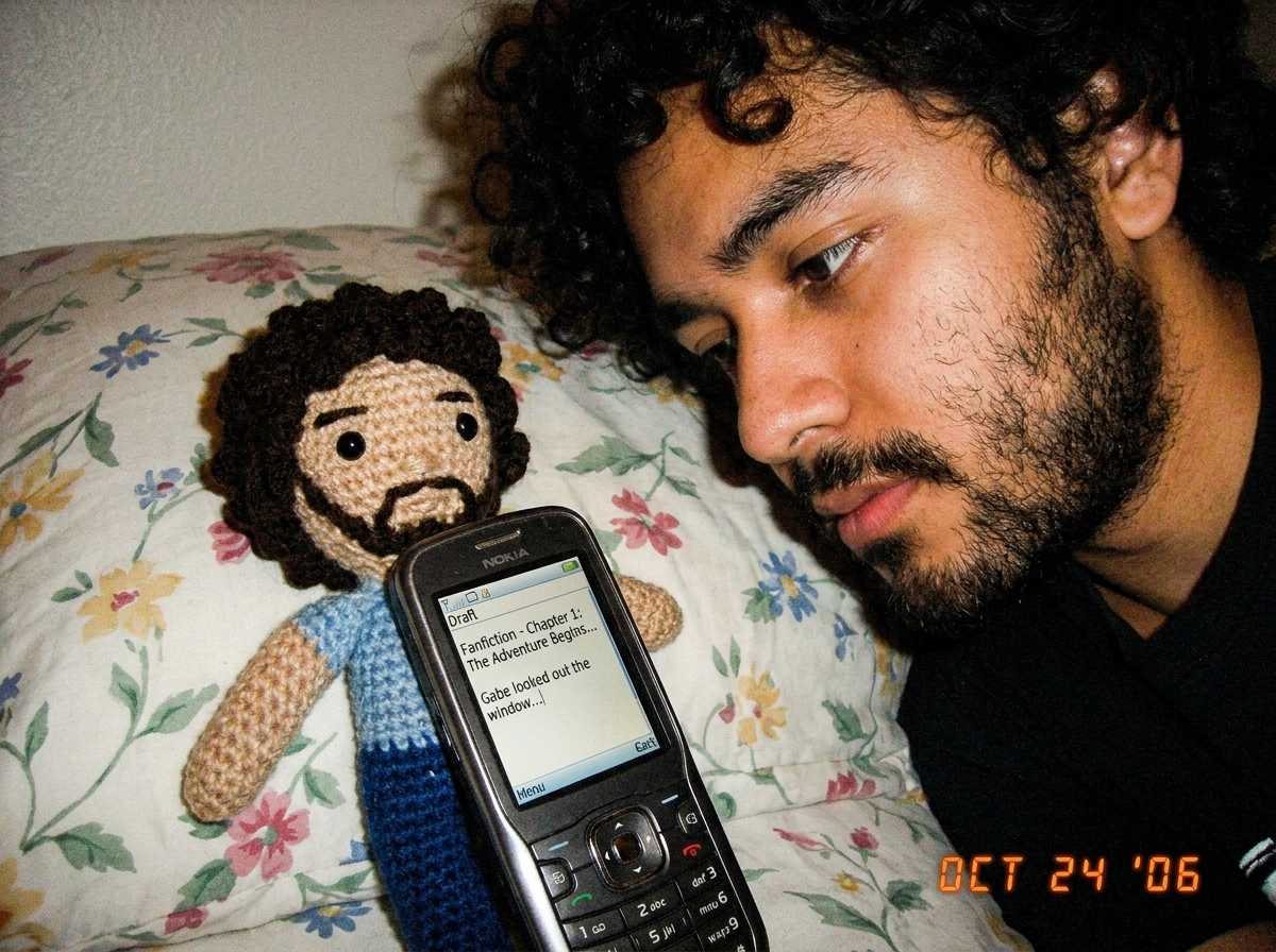 A phone screen showing a draft document with fanfiction text visible, propped up against a crocheted Gabe-able on a bedroom pillow