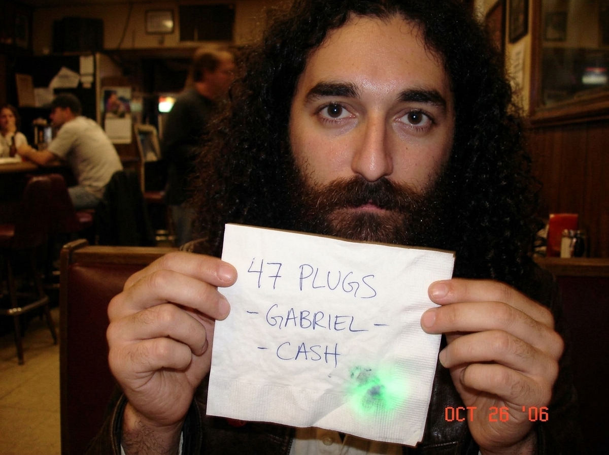 A handwritten note on a crumpled napkin that says '47 PLUGS - GABRIEL - CASH' with a smudge that looks like a green glow in the corner