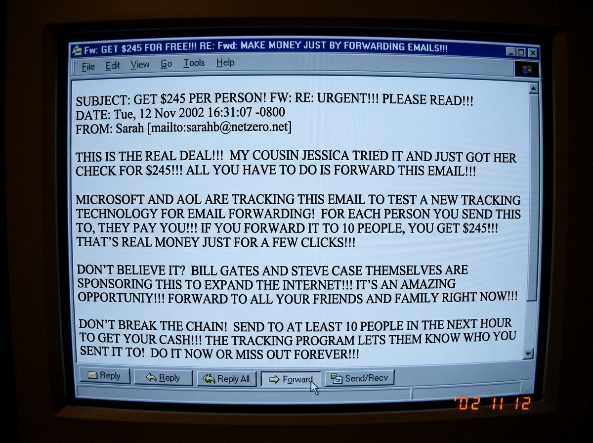 A screenshot of a forwarded chain email from 2002 promising $245 per person if you forward it to friends, full of ALL CAPS text, exclamation marks, and claims about Microsoft and AOL tracking emails, with the cursor hovering over the forward button