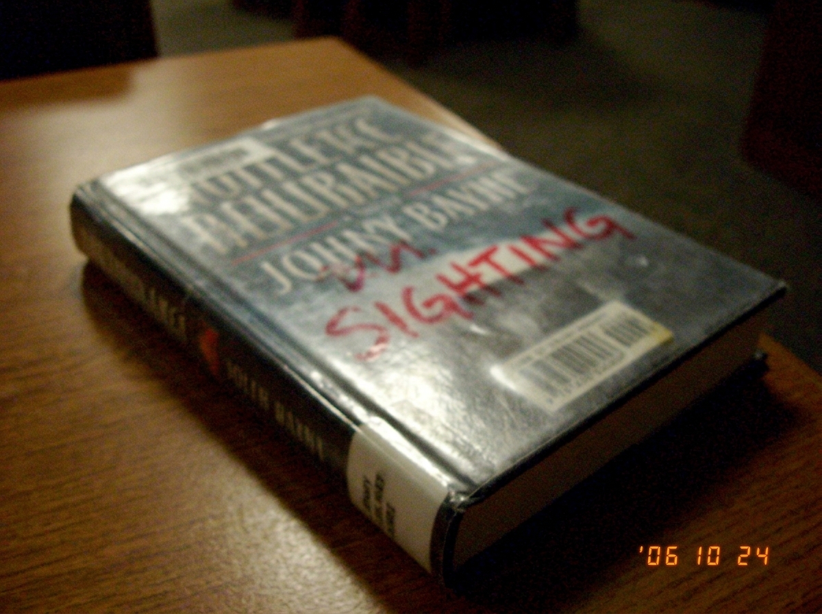 A very blurry photo of a library book with 'SIGHTING' scribbled on the cover in red marker