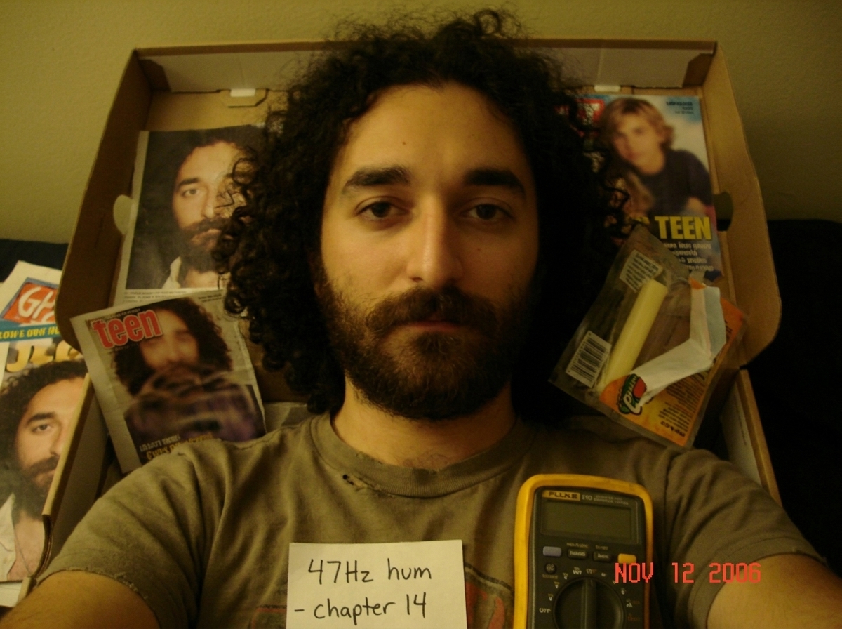 My shoebox altar with Gabriel magazine clippings, the blurry teen magazine photo, string cheese, and a tiny Fluke multimeter next to a handwritten note saying '47Hz hum - chapter 14'