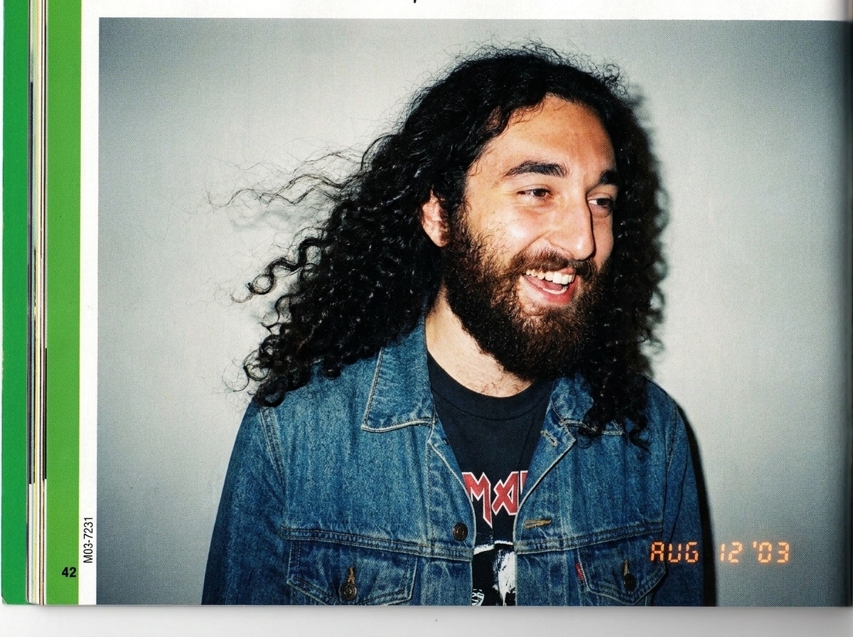 A full-page scan from Teen People magazine, August 2003 issue. Gabriel Chantayan is pictured in a candid shot wearing a denim jacket over a band t-shirt, mid-laugh, wind blowing his hair slightly. The green spine border is visible on the left edge. The magazine's page number and the printer code M03