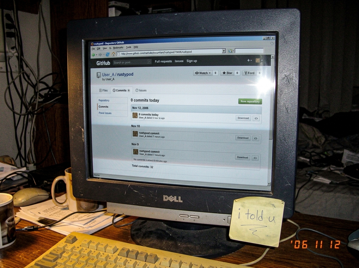 A hastily-taken photo of a computer monitor displaying the rustypod GitHub page showing 0 commits today, with a Post-it note stuck to the bezel that reads 'i told u' in blue pen