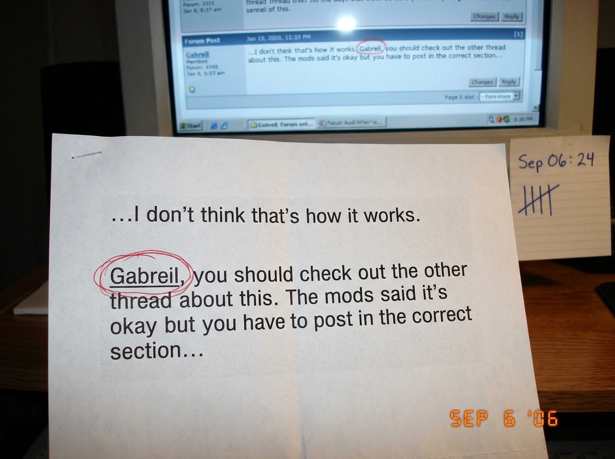 A close-up photo of a forum post printed on paper, with the word 'Gabreil' circled in red ink. Behind the paper is a CRT monitor screen showing the same post. On the desk next to the monitor, a small handwritten tally sheet reads 'Sep 06: 24' in pen.