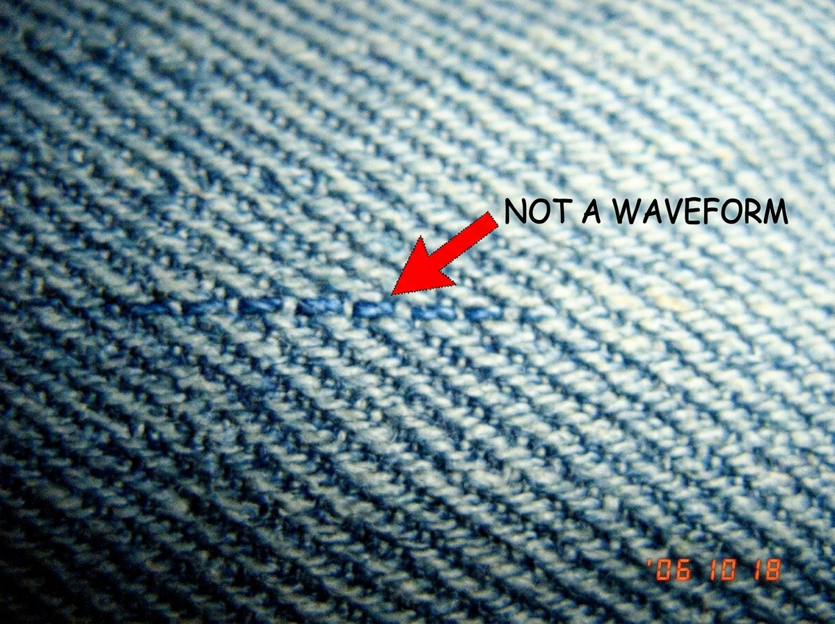 A macro photograph of denim fabric weave showing individual threads, with a red arrow pointing to one thread labeled 'NOT A WAVEFORM' in Comic Sans
