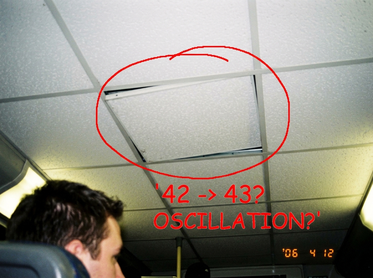 a blurry phone photo of a white ceiling grid with one tile slightly out of alignment, annotated in MS Paint with a red circle around a tile and the text '42 -> 43? OSCILLATION?' in comic sans. the photo is visibly taken from a bus seat at an awkward angle and shows someone else's head in the bottom