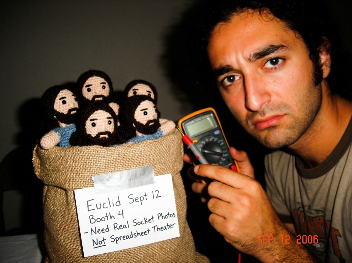 Digital multimeter probe resting next to a burlap sack of crocheted Gabe-ables dolls, with a handwritten note taped to the sack reading 'Euclid Sept 12 Booth 4 - Need Real Socket Photos Not Spreadsheet Theater'