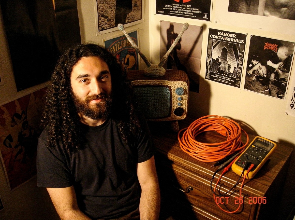 A shrine photo of my Gabriel corner with posters, a crocheted antenna, and my coiled 16awg extension cord sitting next to a Fluke 87V. The light is dramatic :3 :3 :3
