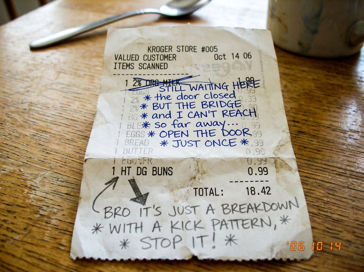 A crumpled Kroger receipt with handwritten lyrics and commentary in two different pens crossing over the printed receipt text. The top half shows 'organic milk 2%' crossed out, replaced with lyric fragments in blue ink about longing and bridges and doors. The bottom half shows 'hot dog buns' printed