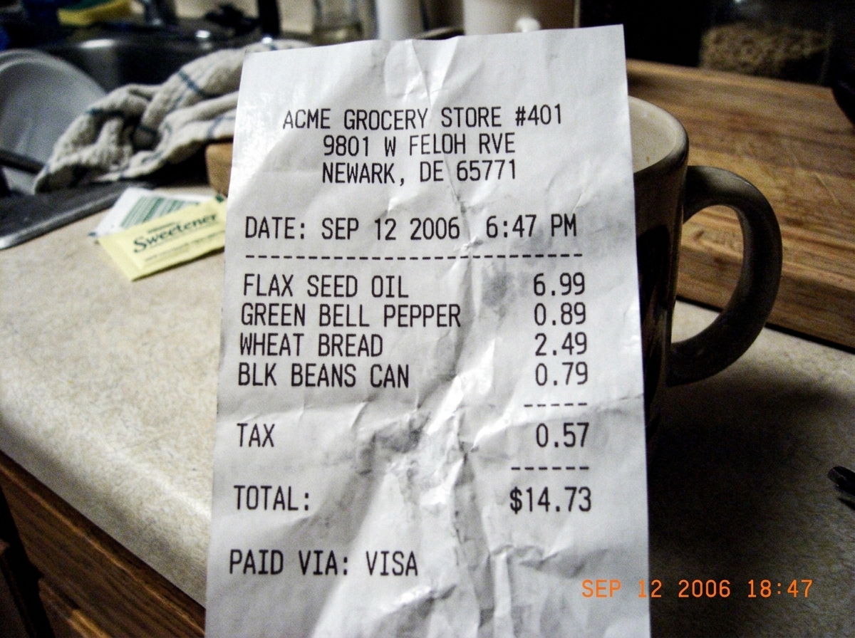 A quick phone photo of a receipt from Acme grocery. Total: $14.73. Item list includes flax seed oil ($6.99), a green bell pepper, a loaf of wheat bread, and a can of black beans. The date and time on the receipt are Sep 12 2006 6:47 PM. The receipt is crumpled slightly, sitting on a kitchen counter 