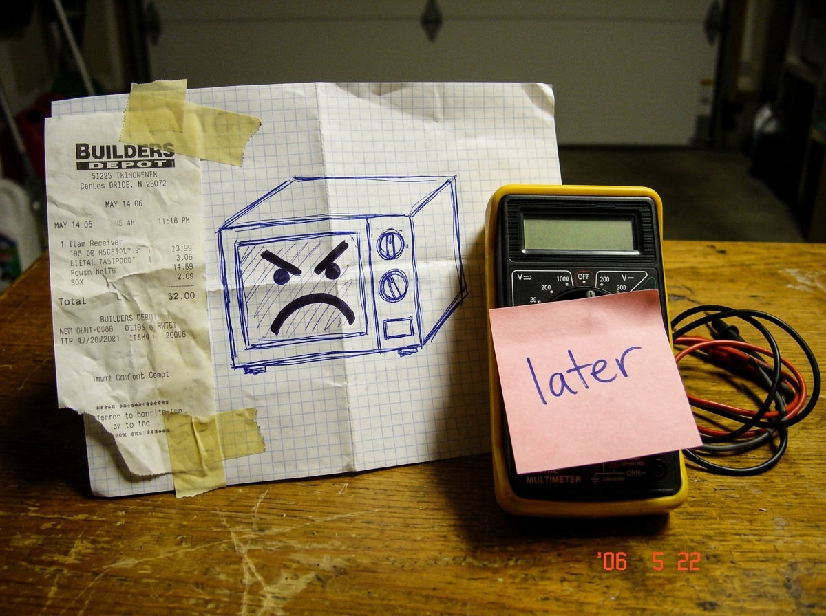A crumpled receipt from a hardware store taped to a wrinkled drawing of a microwave with a frowny face drawn in marker, next to a multimeter that has a sticky note on it that just says 'later' in handwriting