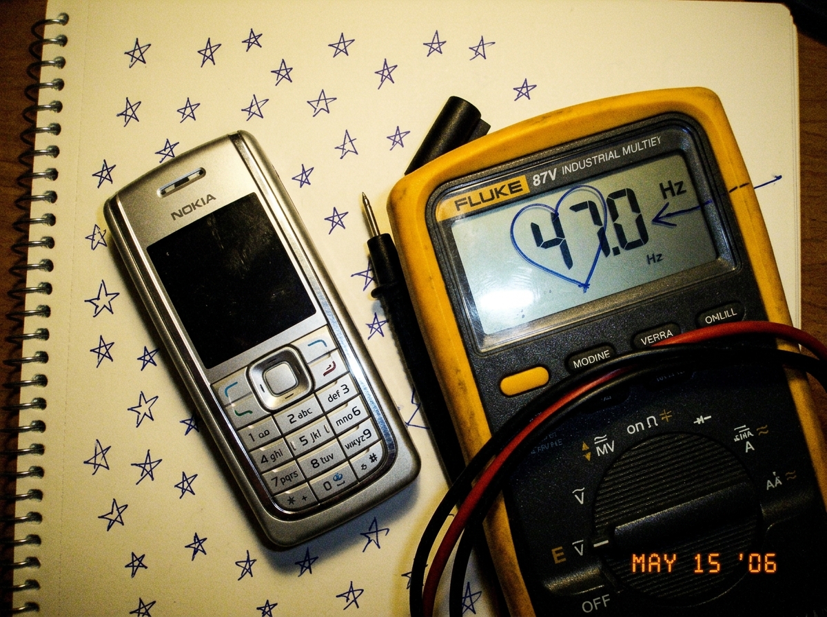 My phone resting on a notebook page covered in tiny star doodles, next to a Fluke 87V showing 47.0 Hz on the display, with a small hand-drawn arrow pointing at the number and a heart around '47'