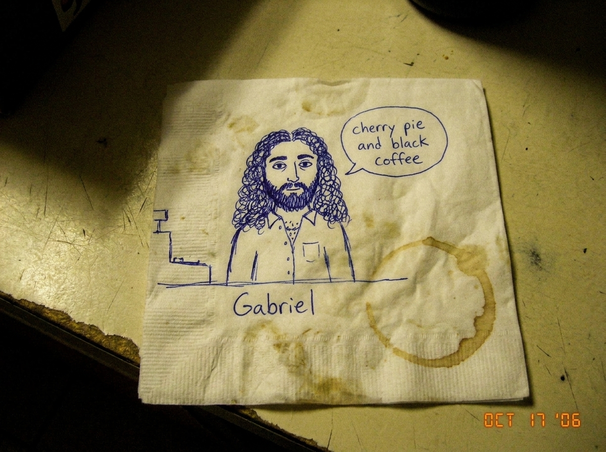 A greasy gas station napkin with a ballpoint pen doodle of a figure labeled 'Gabriel' standing at a counter, with a speech bubble saying 'cherry pie and black coffee'. The napkin is crumpled and has a small coffee ring stain in the corner.
